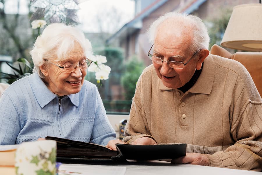 Una pareja de ancianos se sumerge en la lectura de un libro juntos, destacando la importancia de la conexión y el cuidado en nuestra página web de cuidado para mayores, cuidado de personas dependientes y cuidados paliativos